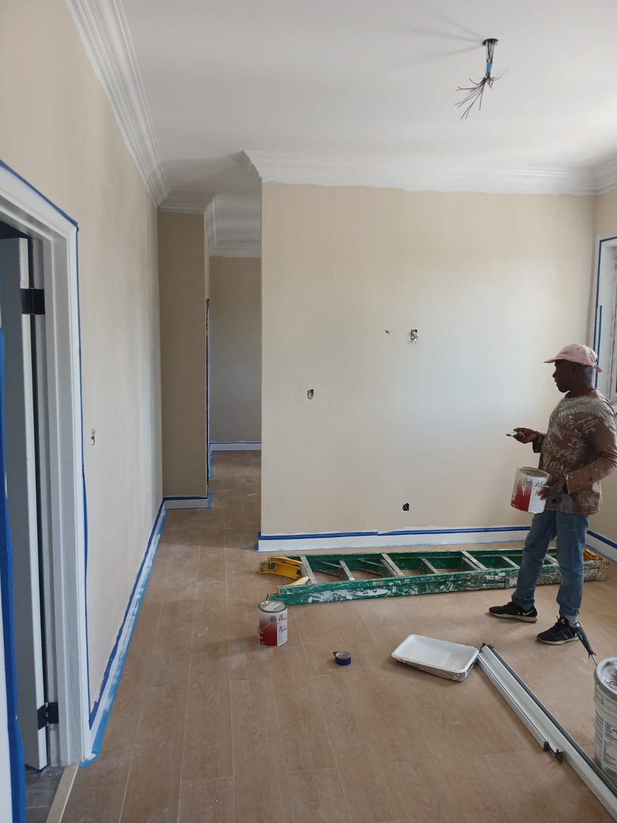 Painter cutting in a hallway with crown molding