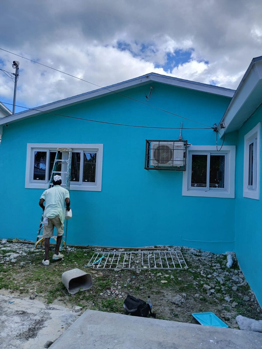 Painter rolling a teal exterior wall