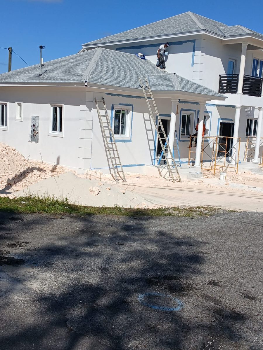 Crew painting a home exterior from the roofline