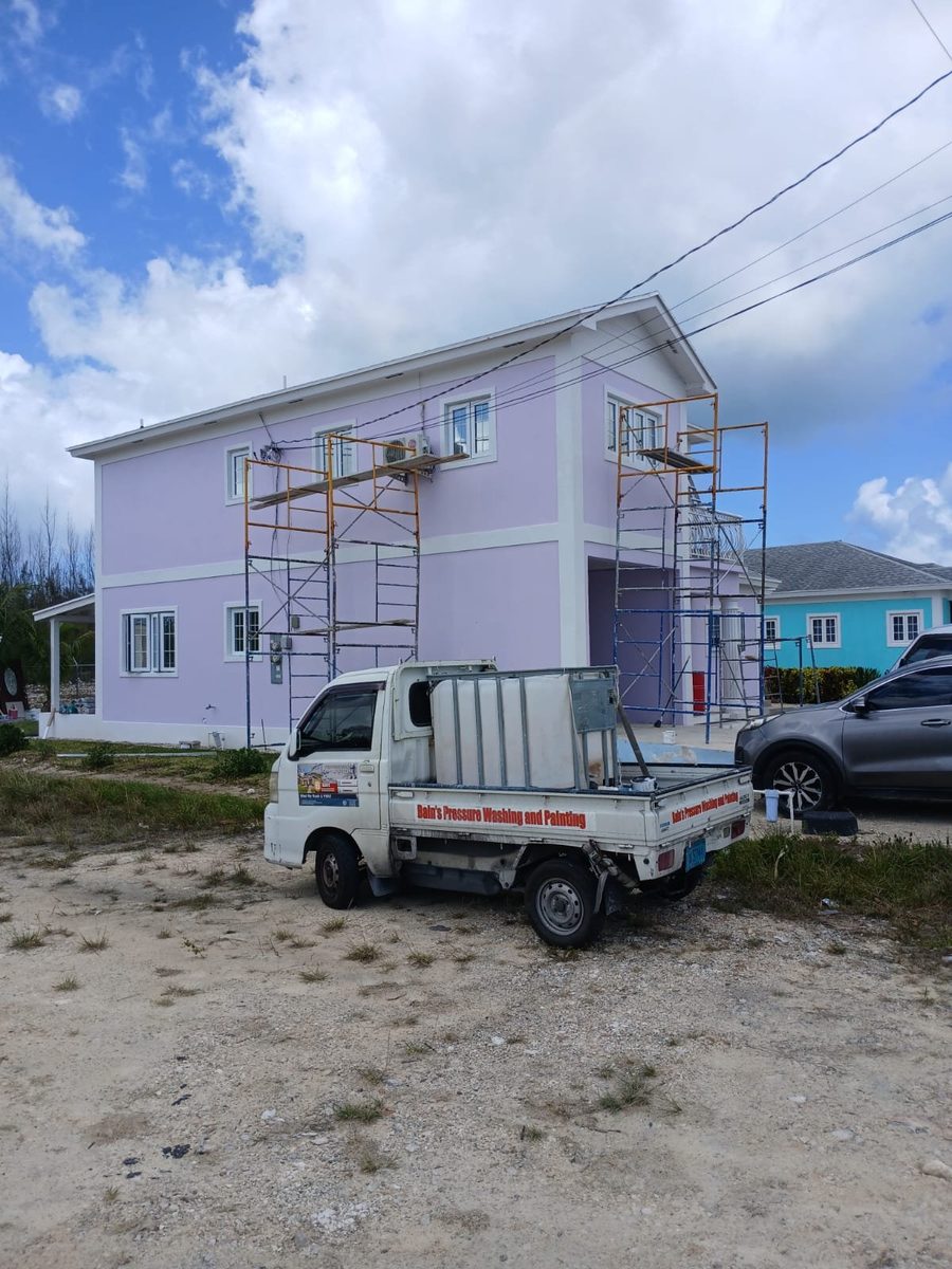 Scaffold set up against a lavender two-story with company truck